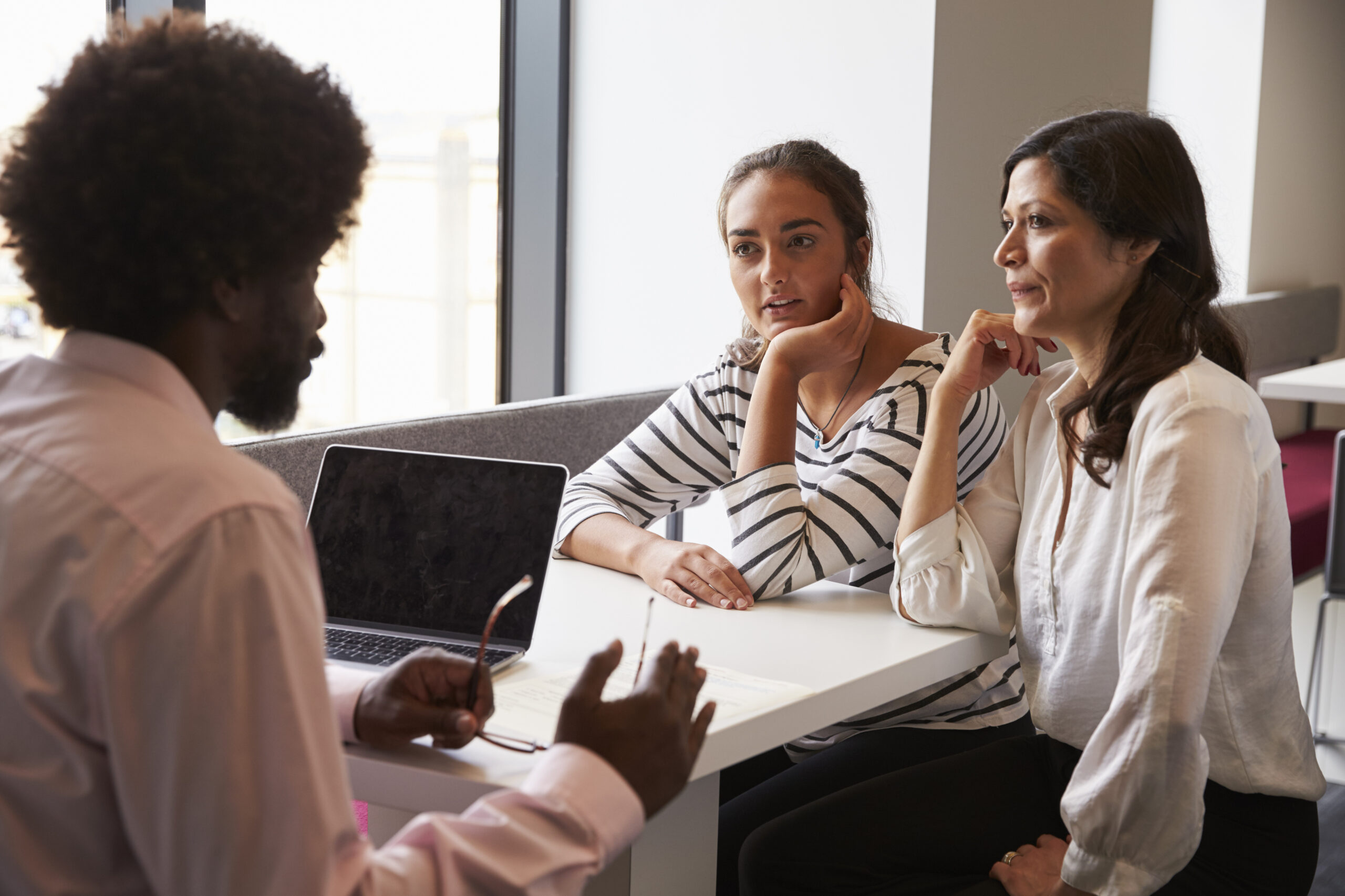 A woman banker talking to a mother and her daughter.