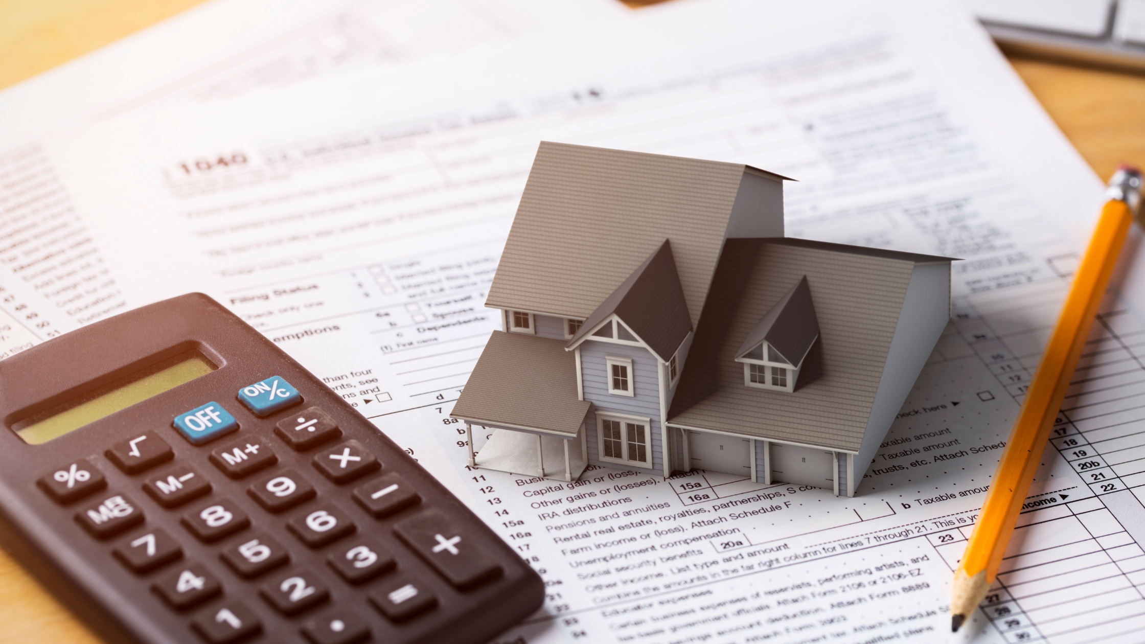 Small model house with a calculator on loan paperwork