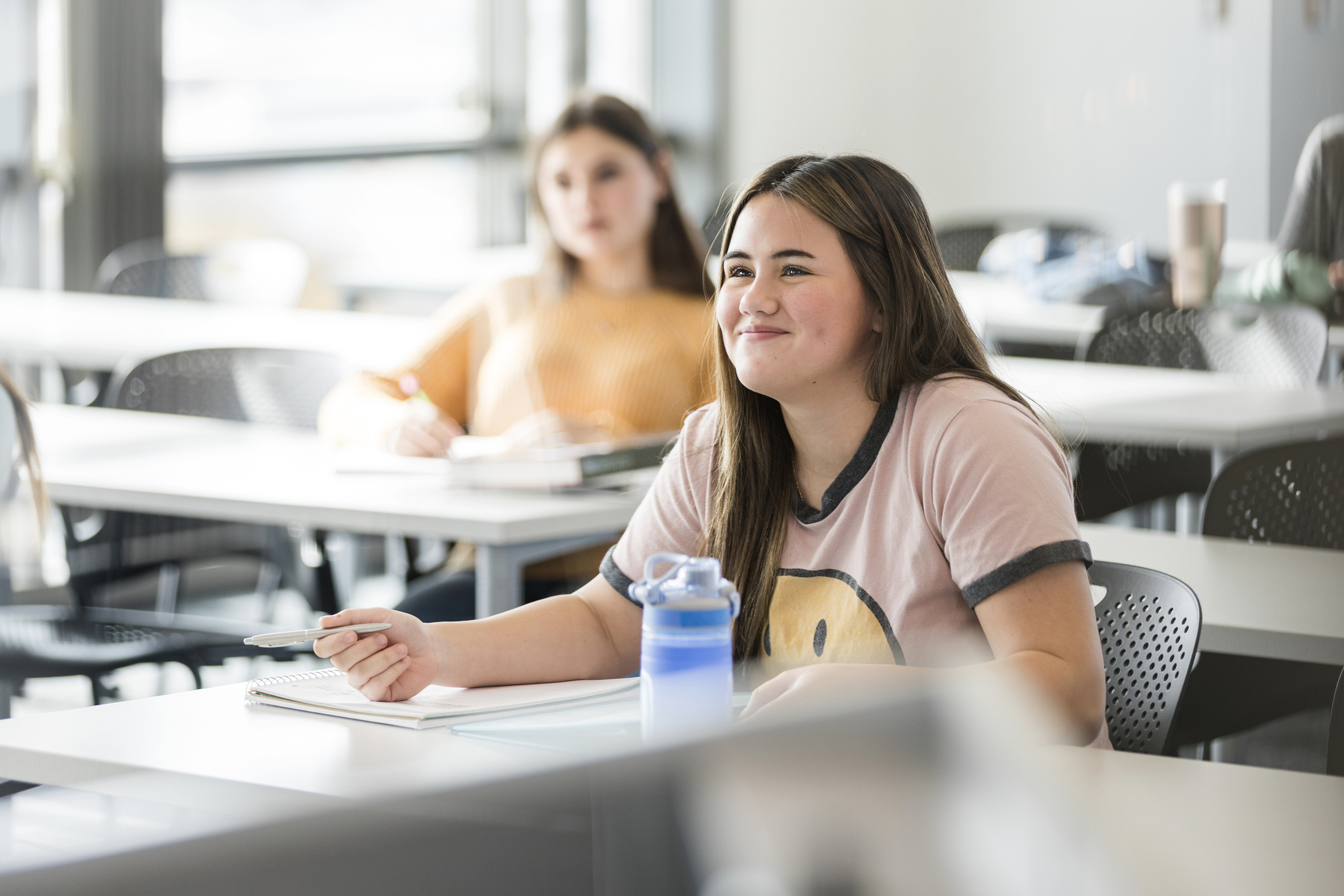 Young adult female university student smiles while listening to the unseen speaker